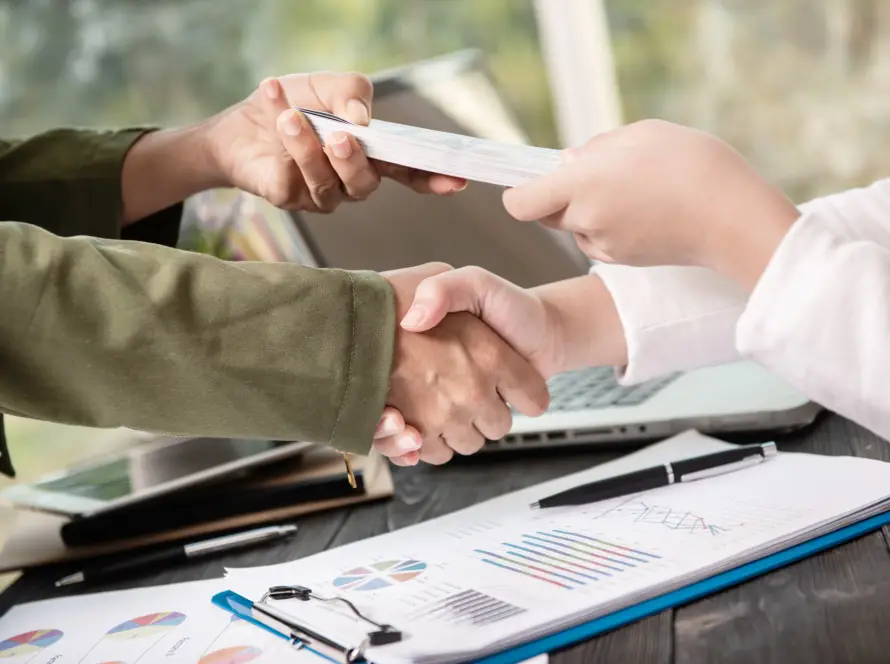 Two professionals shaking hands after discussing payroll services.